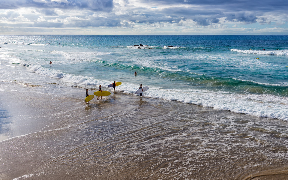 Spanien, Kanarische Inseln, Fuerteventura, La Pared. Eine Gruppe von Jungen geht surfen.